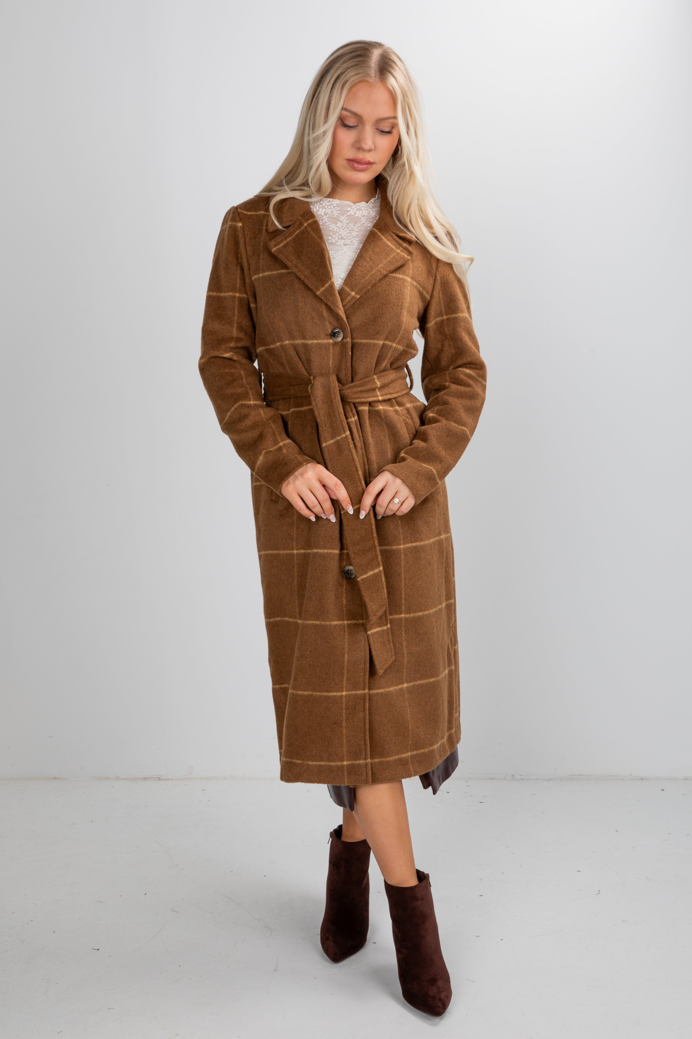 Woman wearing a brown plaid coat with a white background