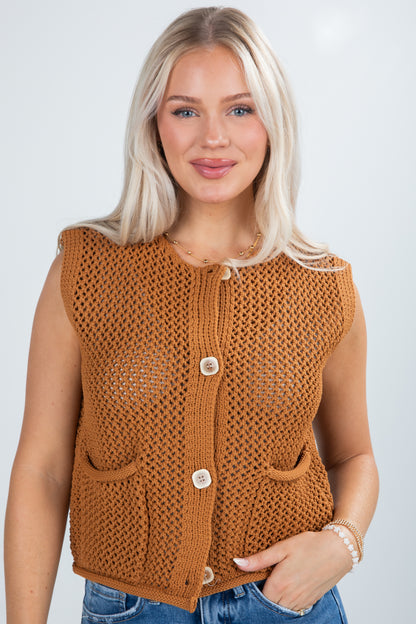 Woman wearing a brown knitted vest with a plain background