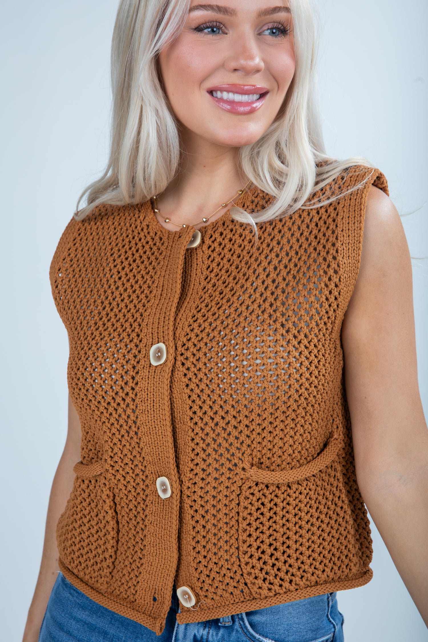 Woman wearing a brown knitted vest against a plain background