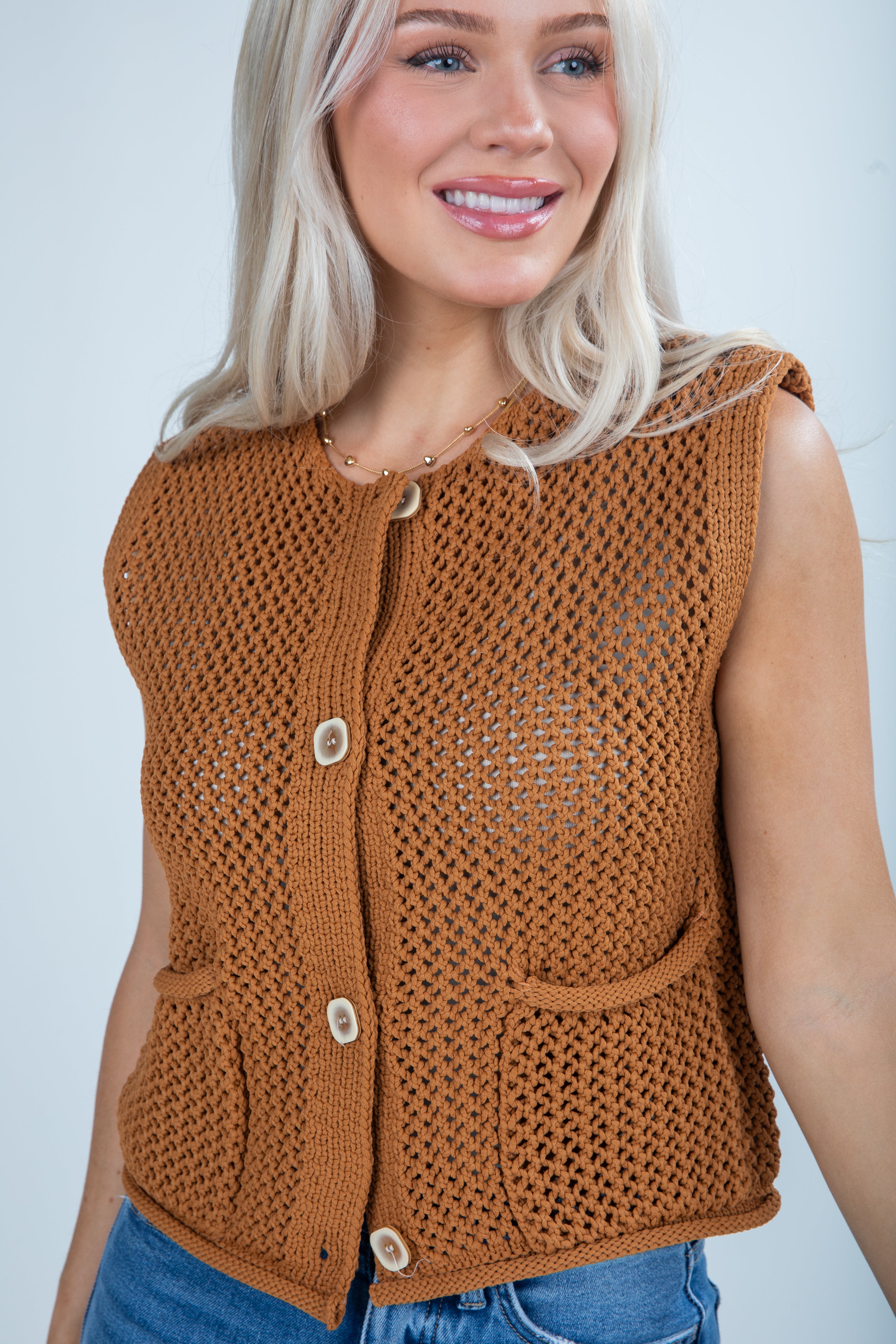 Woman wearing a brown knitted vest against a plain background