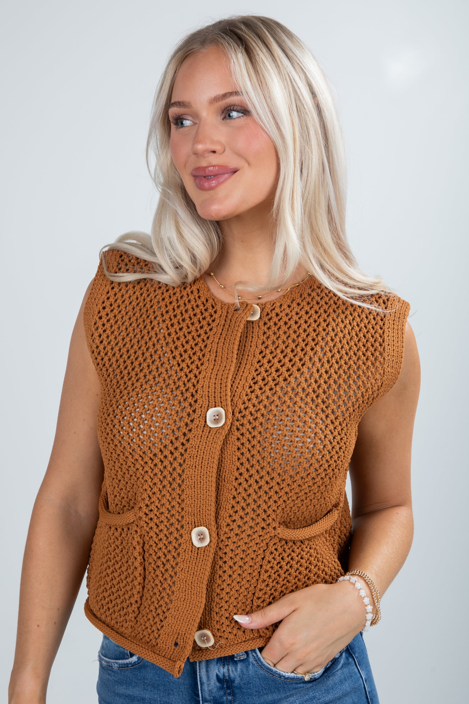Woman wearing a brown knitted vest against a plain background