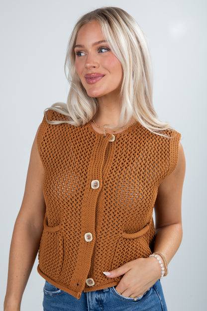 Woman wearing a brown knitted vest against a plain background