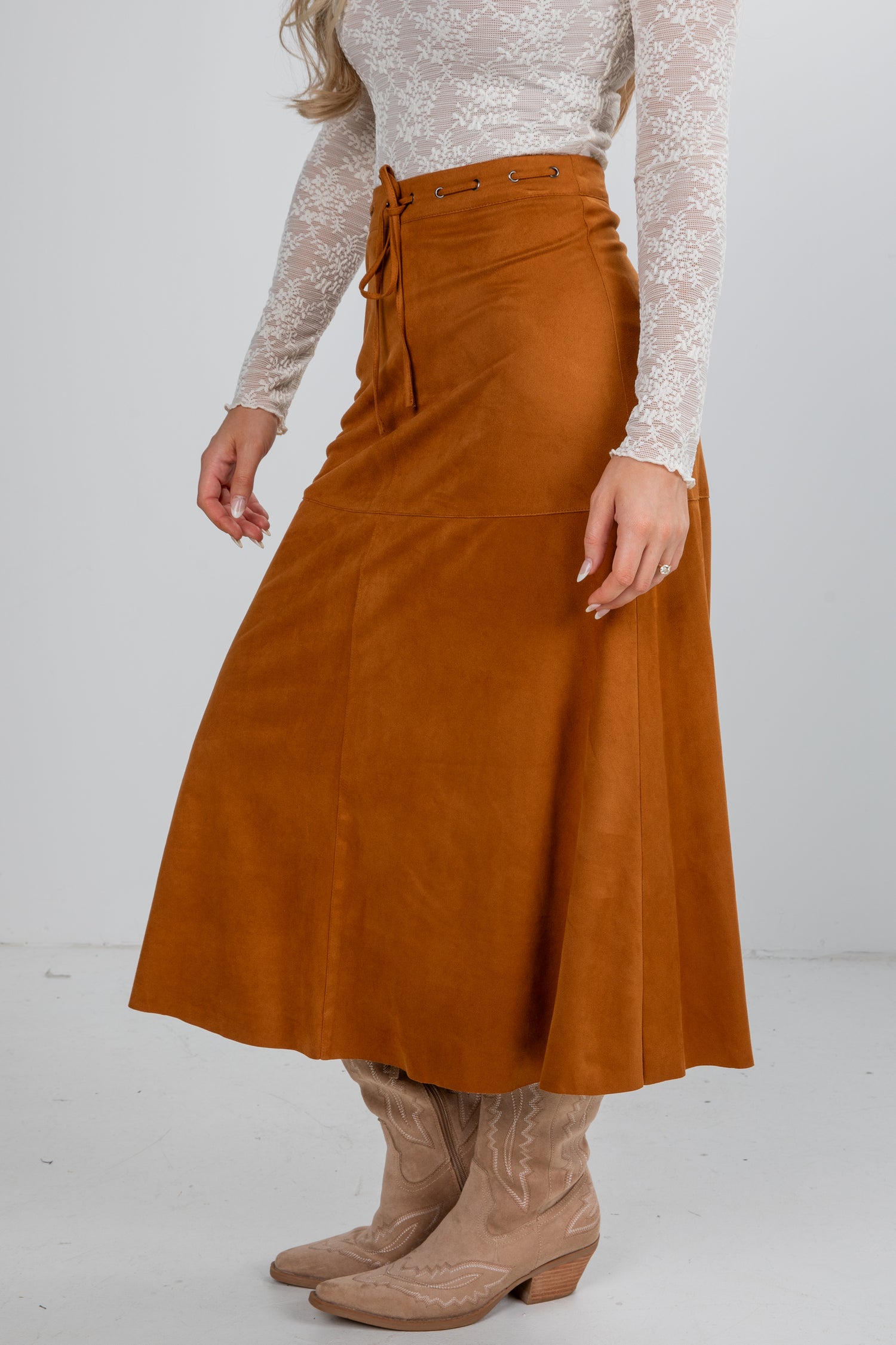 Person wearing a brown skirt and beige boots on a white background