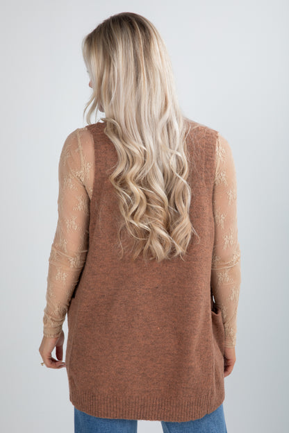 Person wearing a brown cardigan with floral sleeves on a plain background