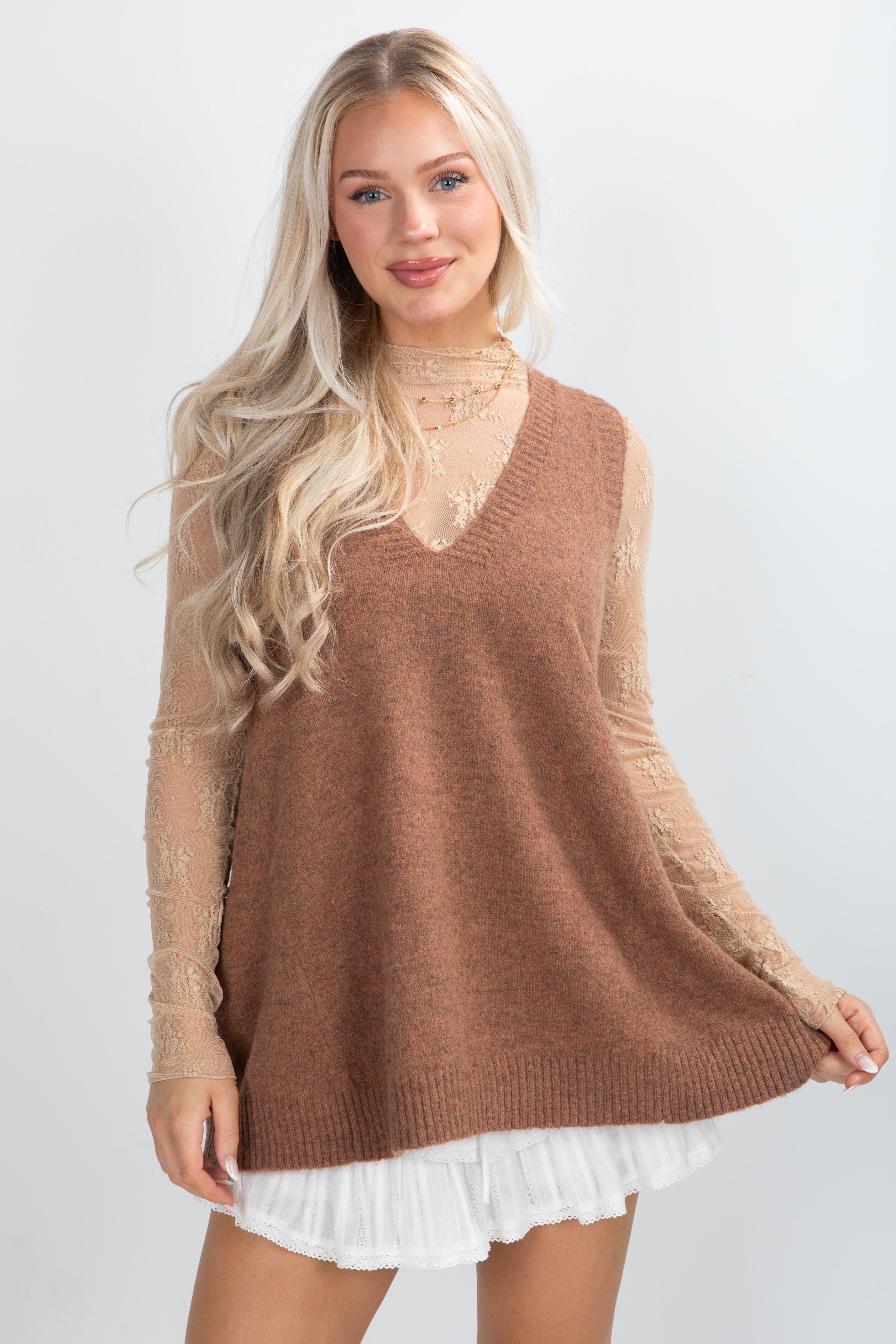 Woman wearing a brown sweater with lace sleeves on a white background