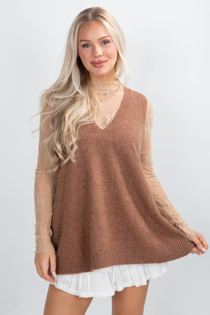 Woman wearing a brown sweater with lace sleeves on a white background