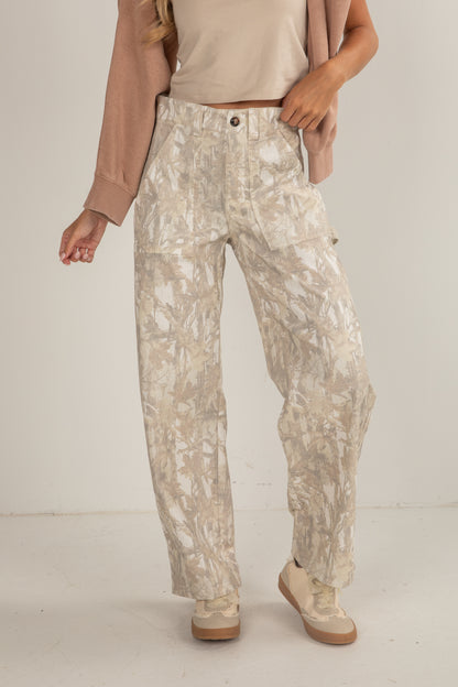 Person wearing beige camouflage pants on a plain background