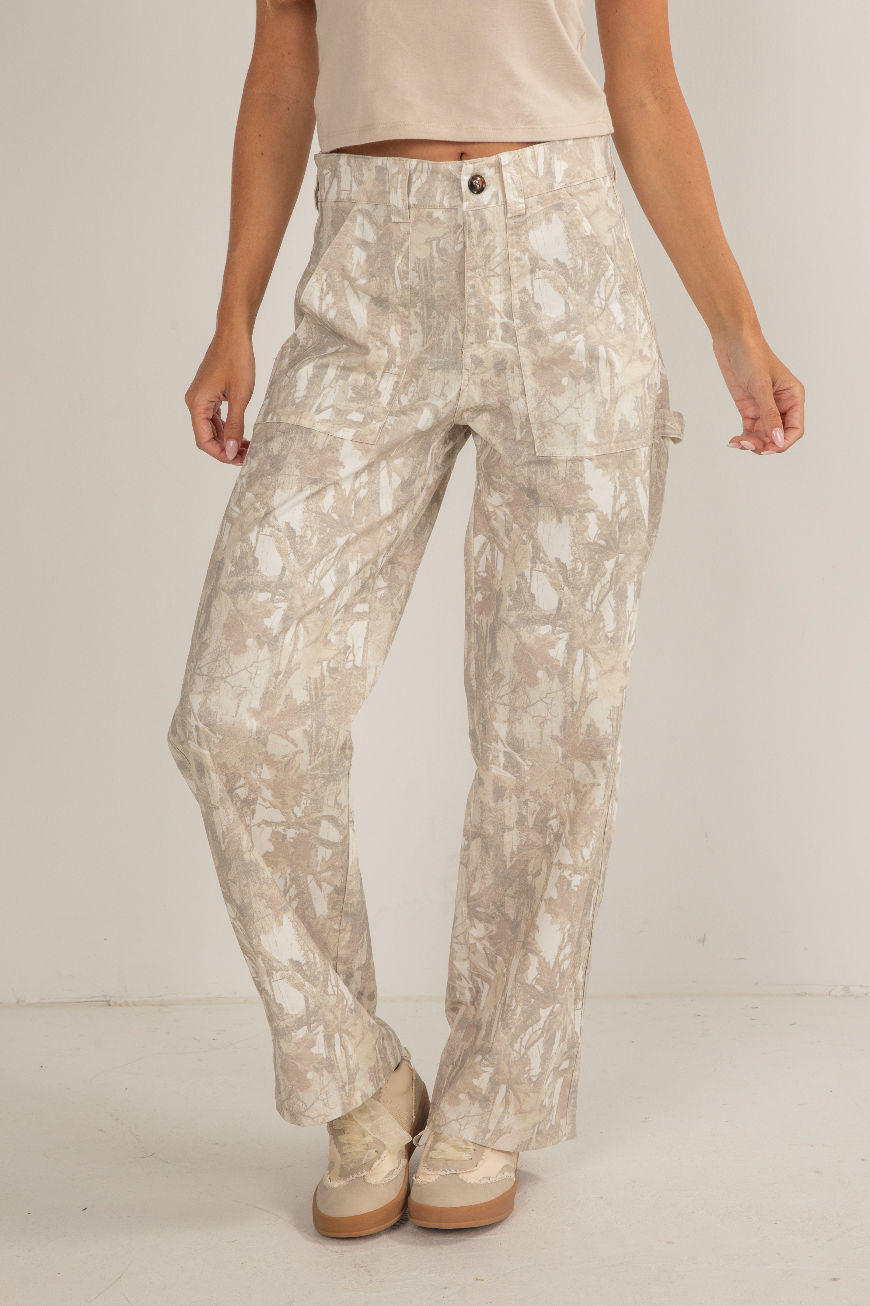 Person wearing beige floral pants on a plain background