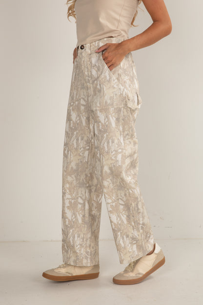 Person wearing beige patterned pants and matching shoes on a plain background