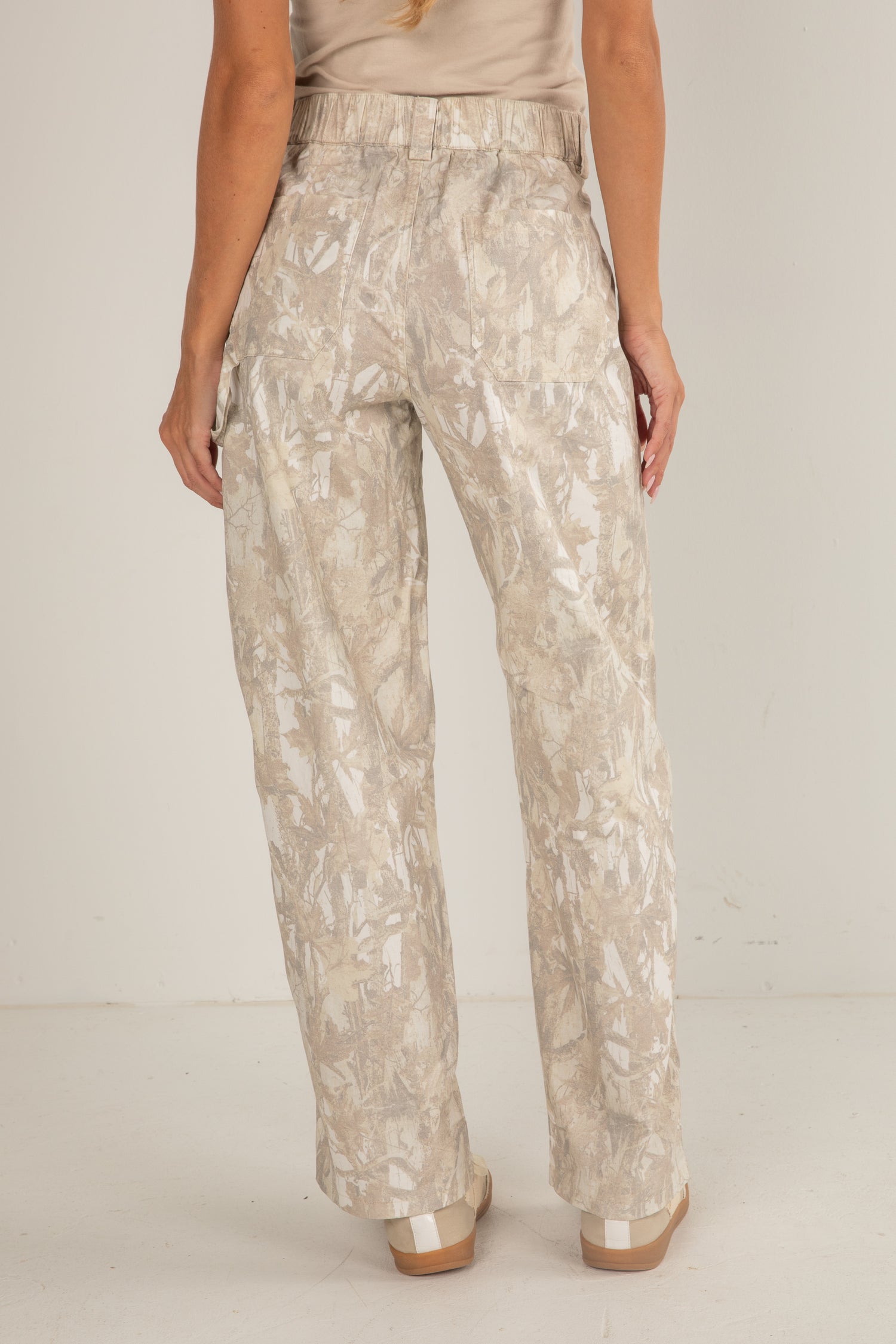 Person wearing beige floral pants on a plain background