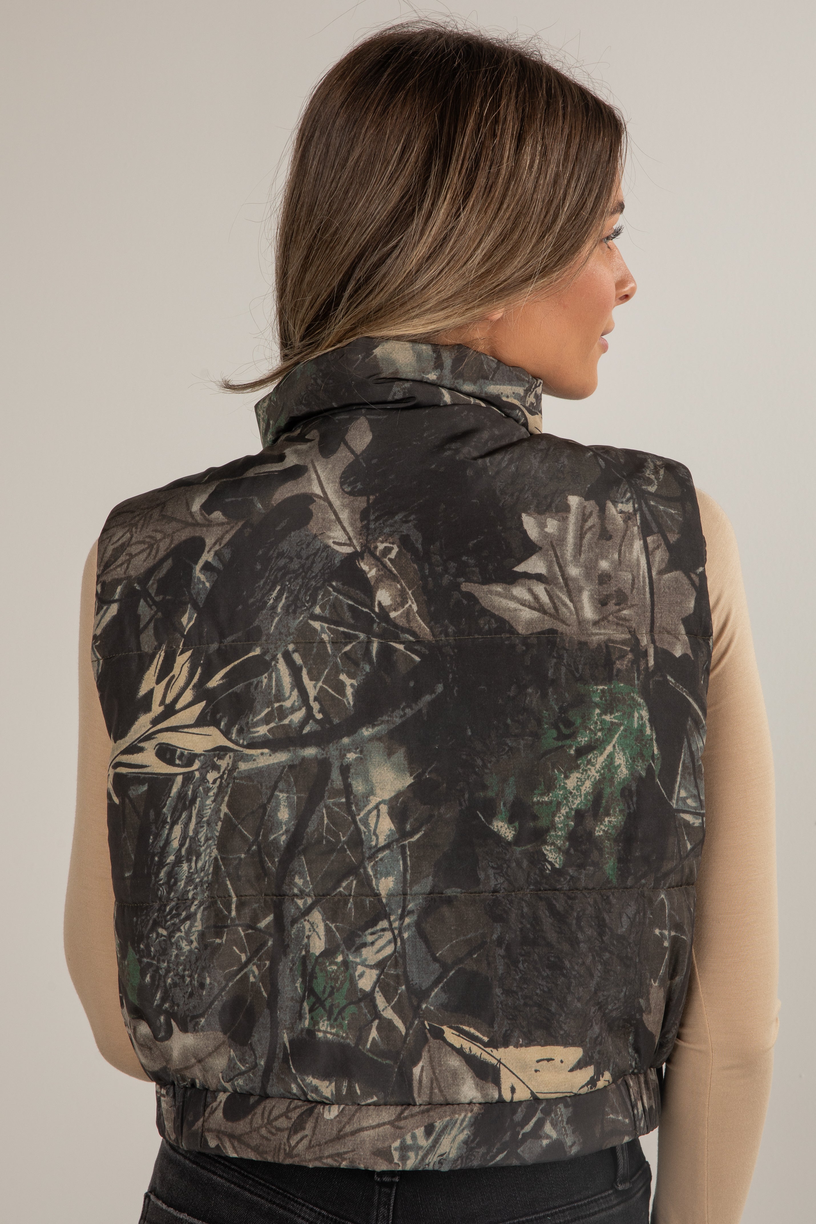 Woman wearing a camouflage vest on a plain background