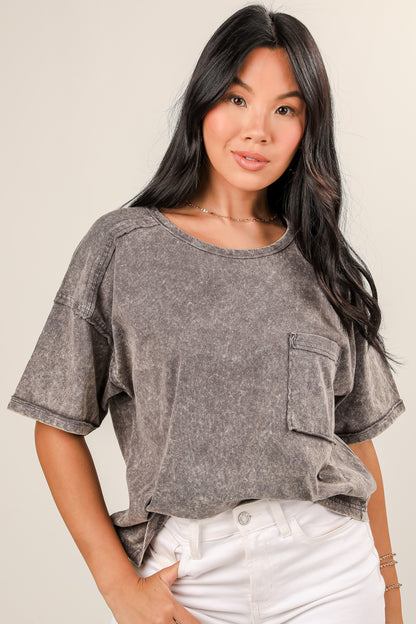 Woman wearing a gray distressed shirt with rolled-up sleeves on a plain background