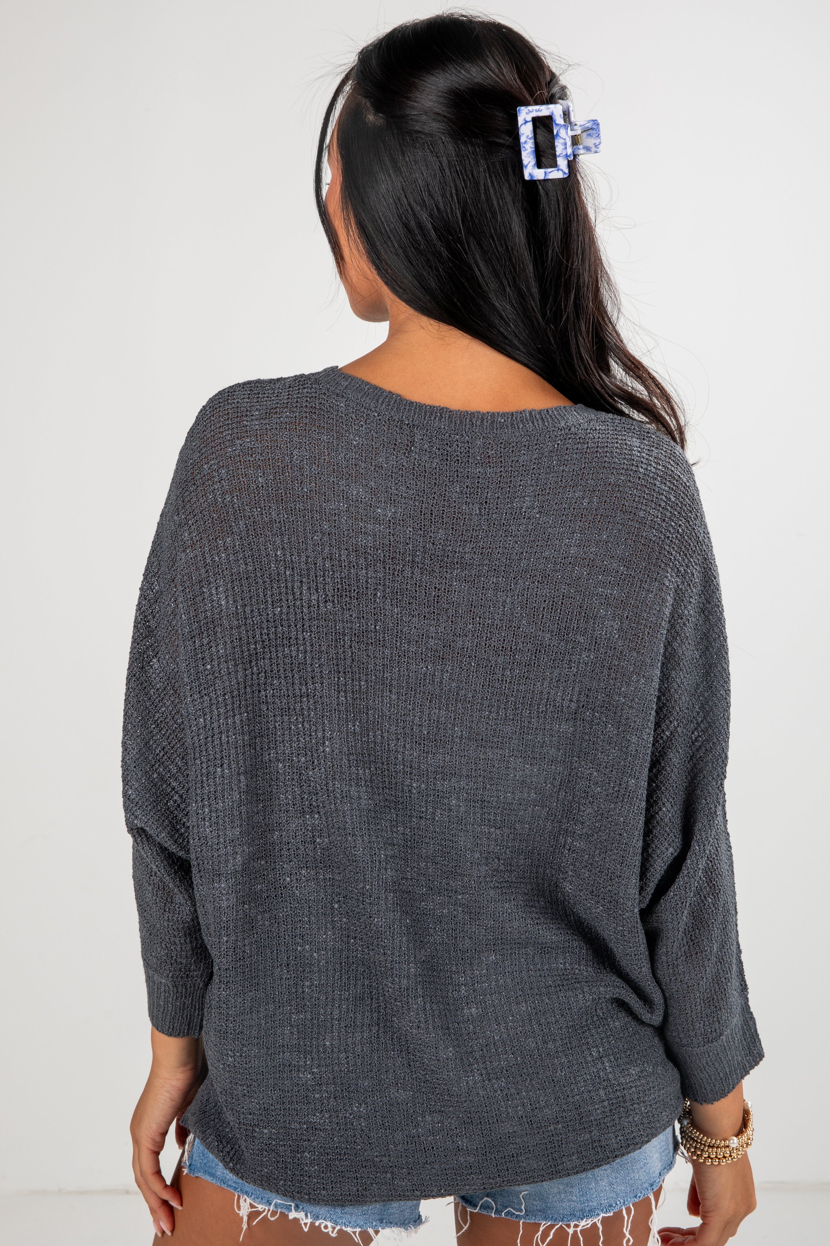 Person wearing a dark gray sweater with a plain background