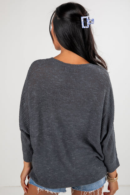 Person wearing a dark gray sweater with a plain background