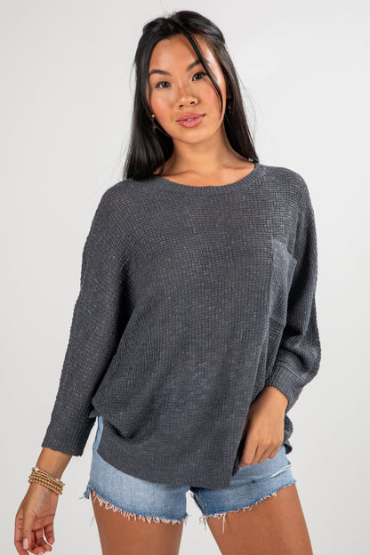 Woman wearing a gray sweater and denim shorts on a white background