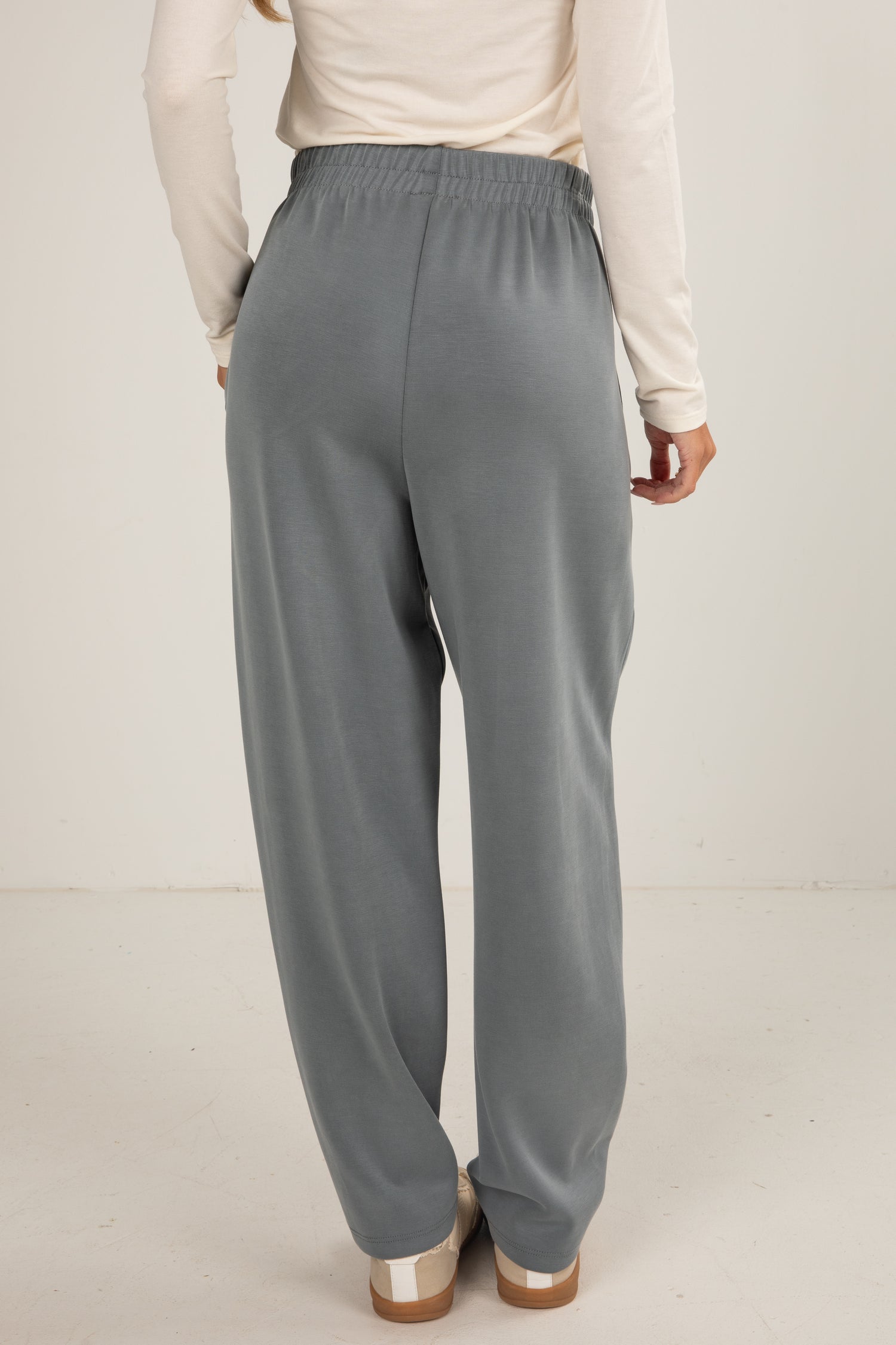 Person wearing gray pants and a light-colored top on a plain background