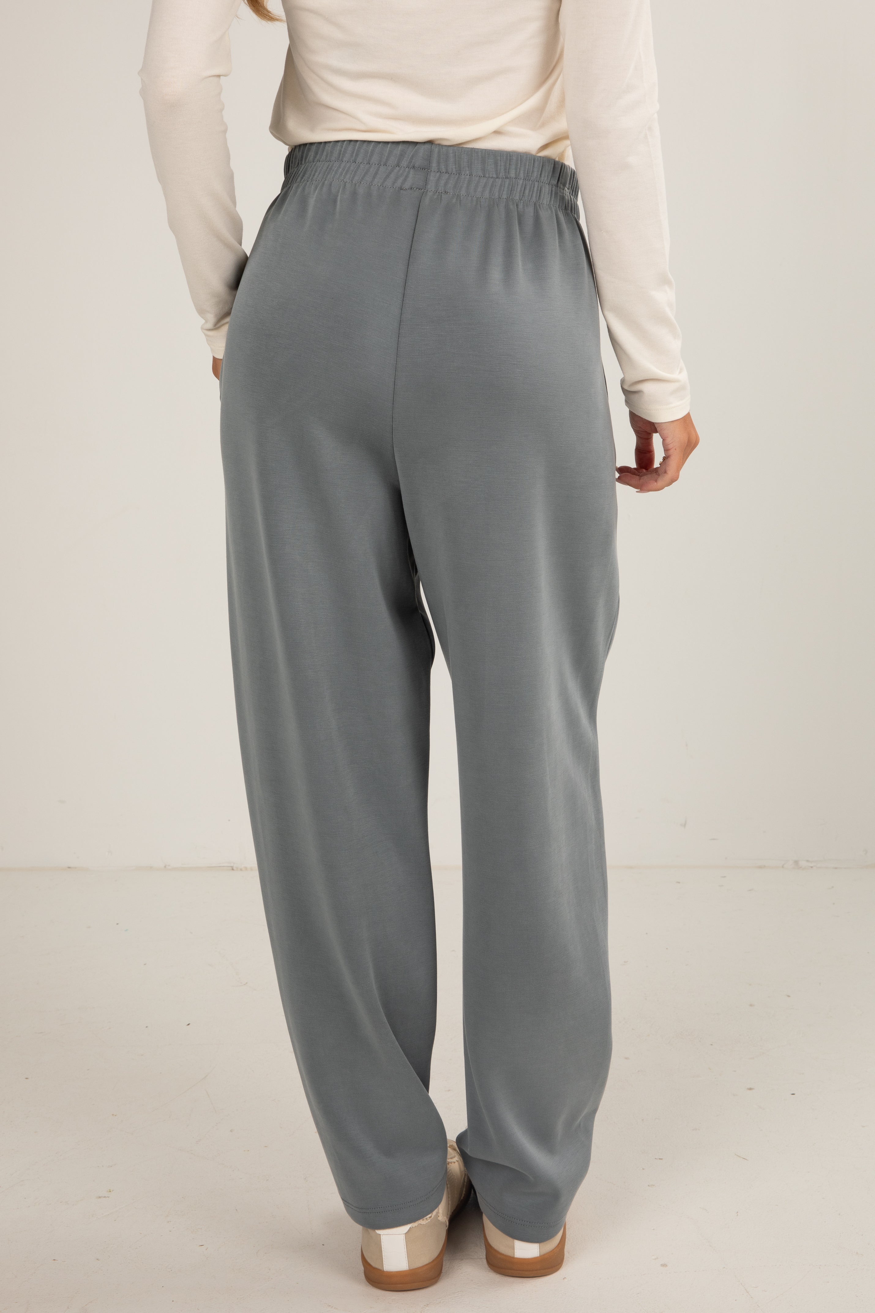 Person wearing gray pants and a light-colored top on a plain background