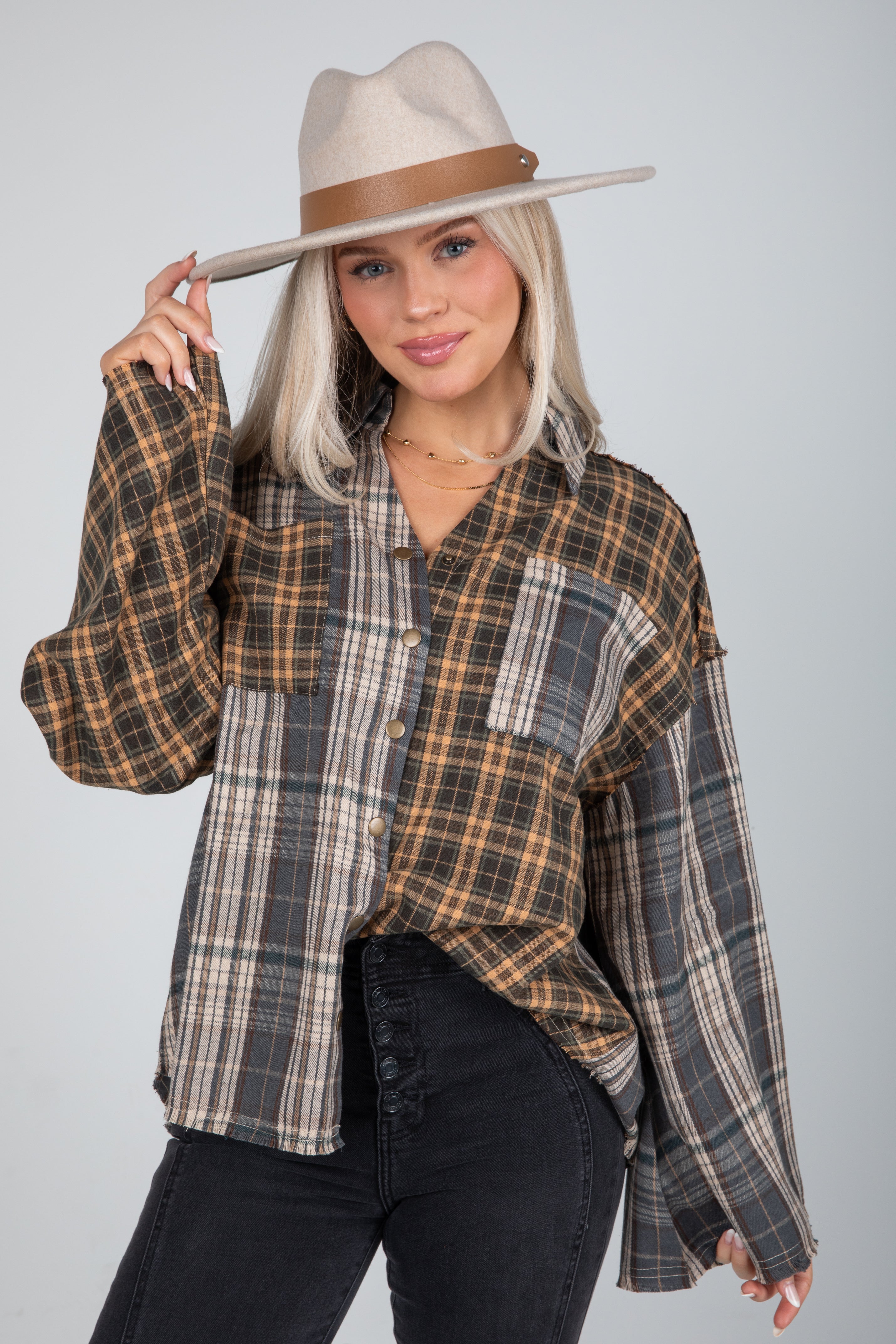 Woman wearing a plaid shirt and hat on a gray background