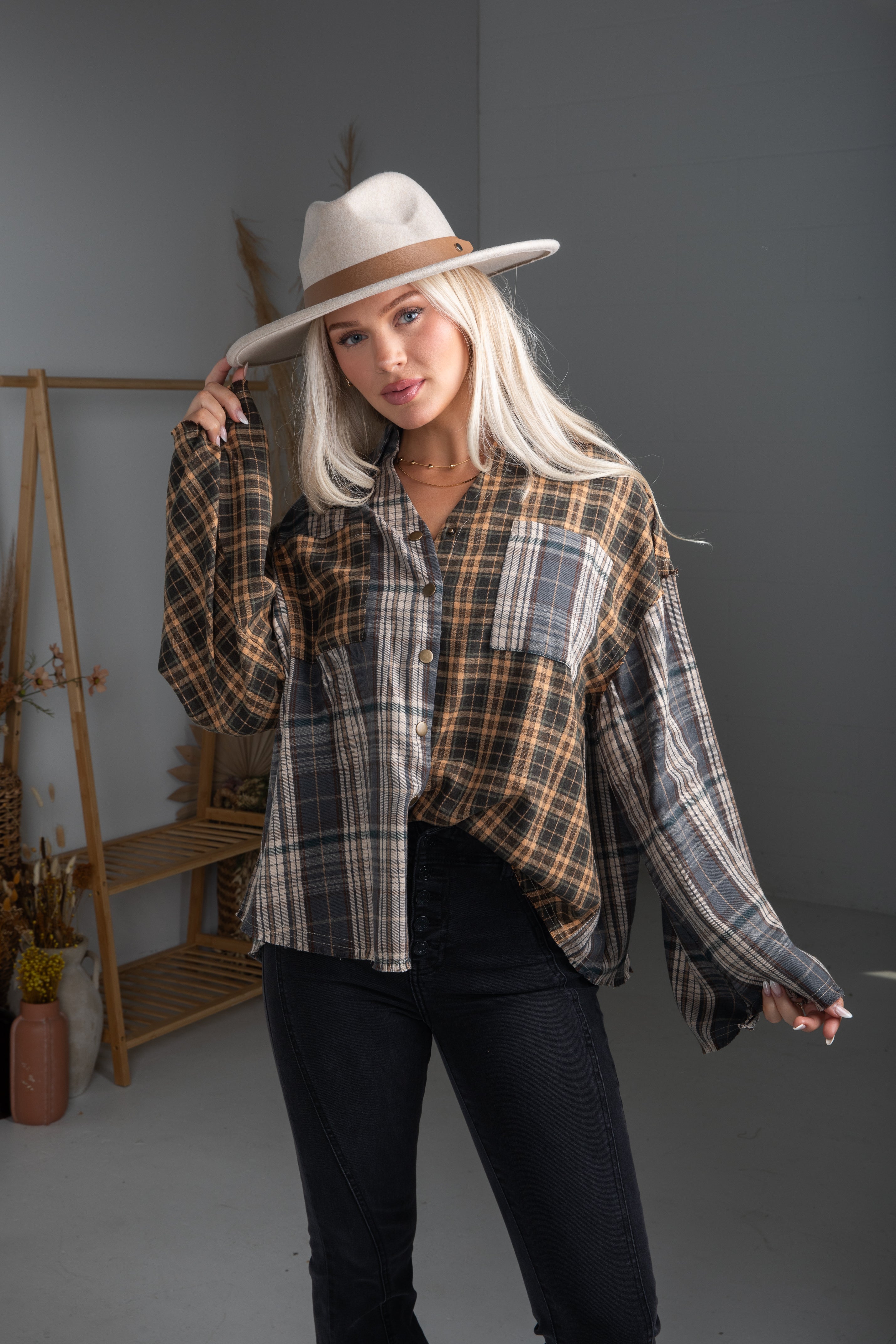 Woman wearing a plaid shirt and hat in a studio setting