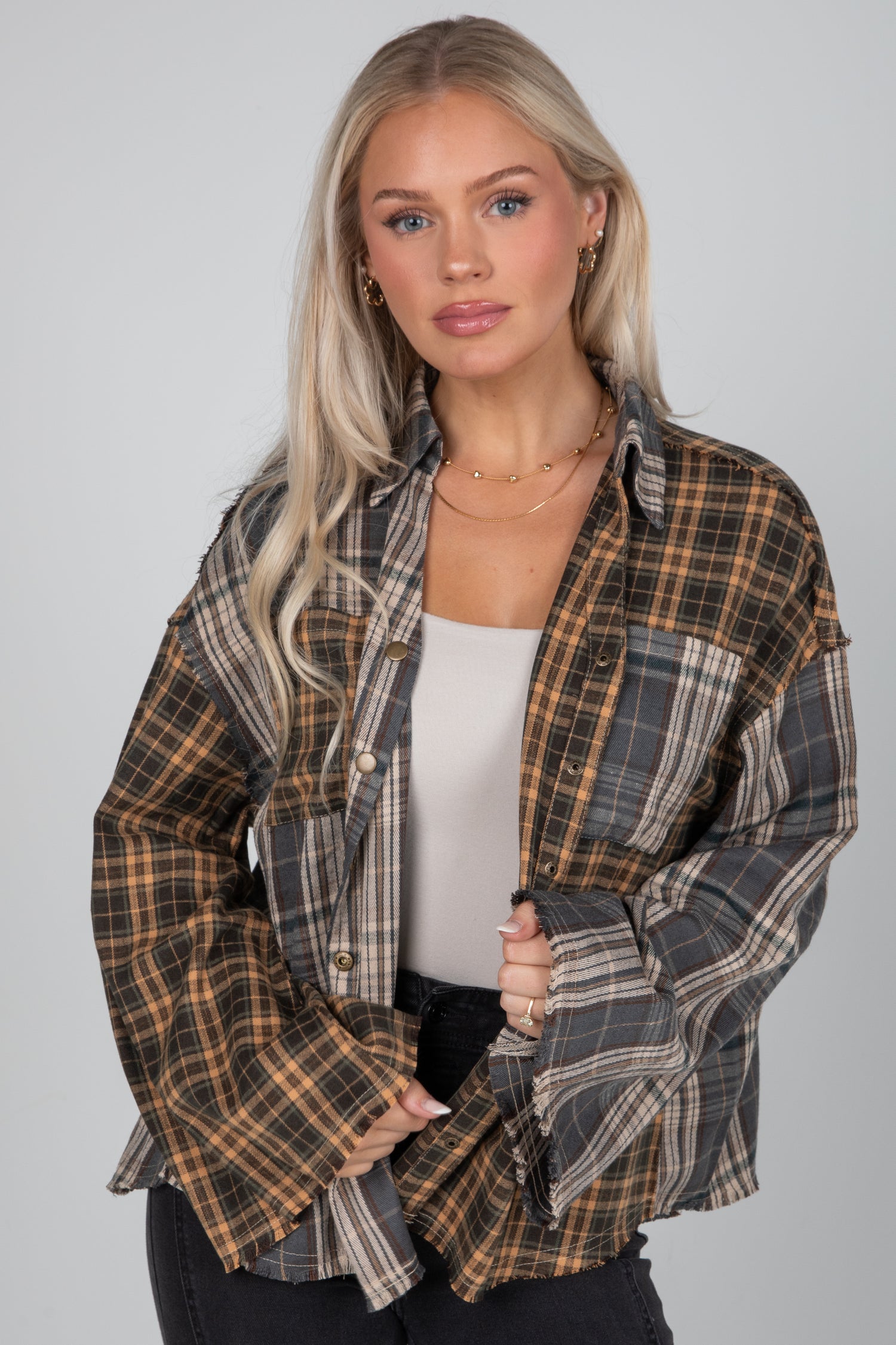 Woman wearing a plaid shirt over a white top on a gray background