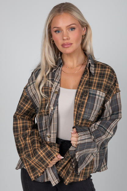 Woman wearing a plaid shirt over a white top on a gray background