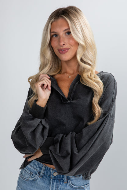 Woman wearing a black oversized sweater and blue jeans on a plain background