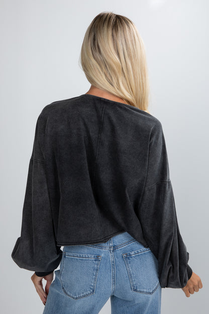 Person wearing a black oversized sweater and blue jeans on a plain background