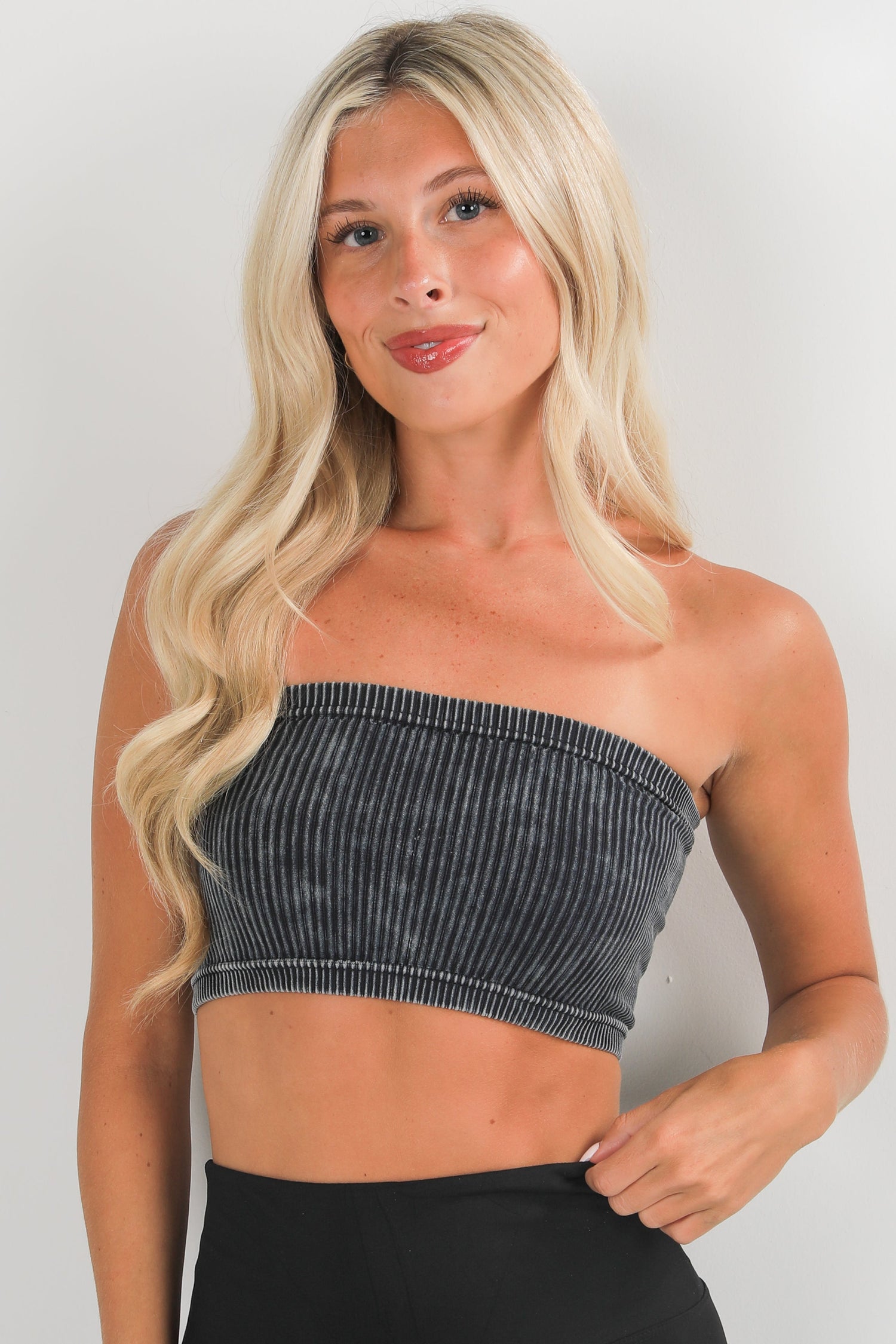 Woman wearing a strapless denim top against a plain background