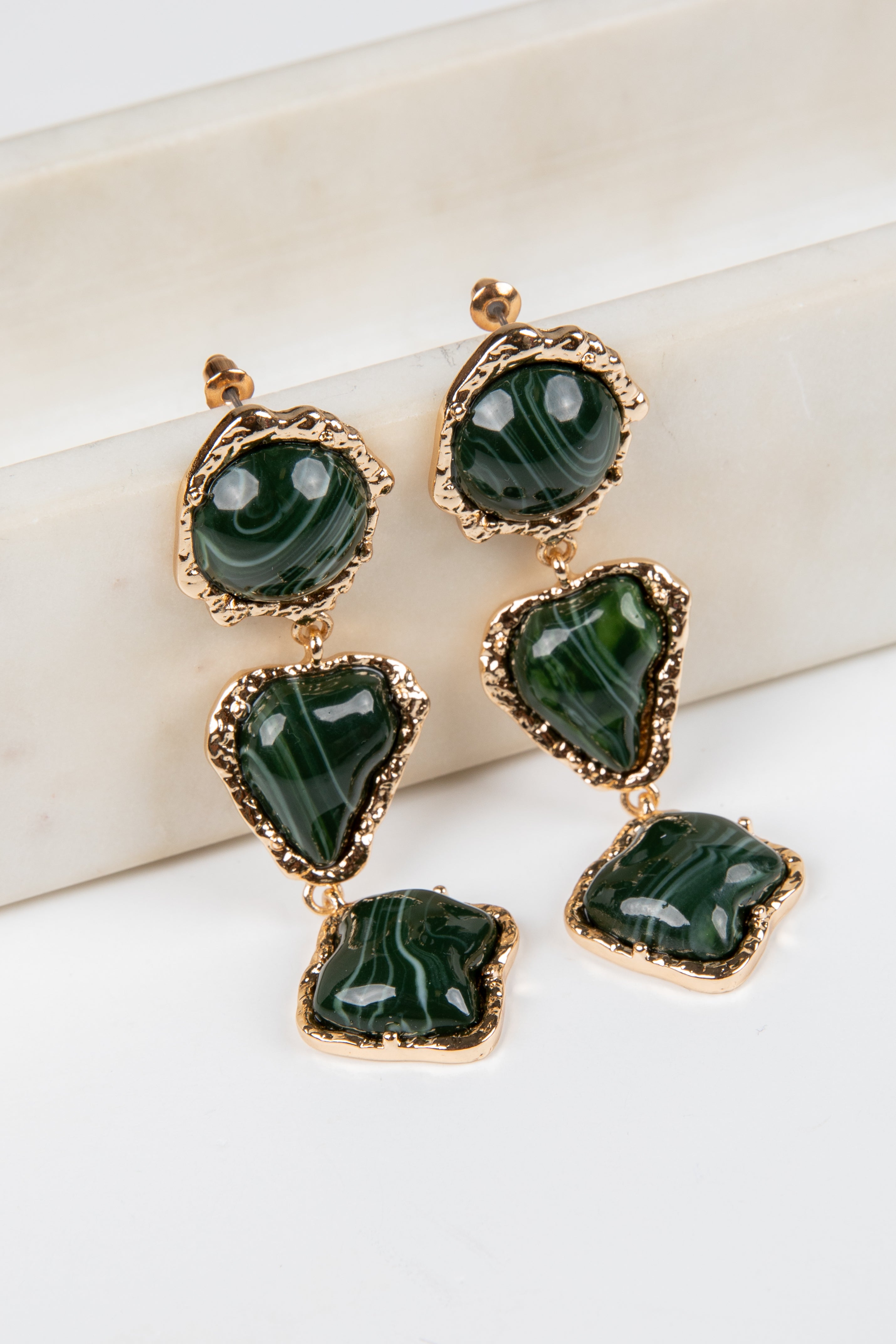 Green gemstone earrings with gold accents on a white background