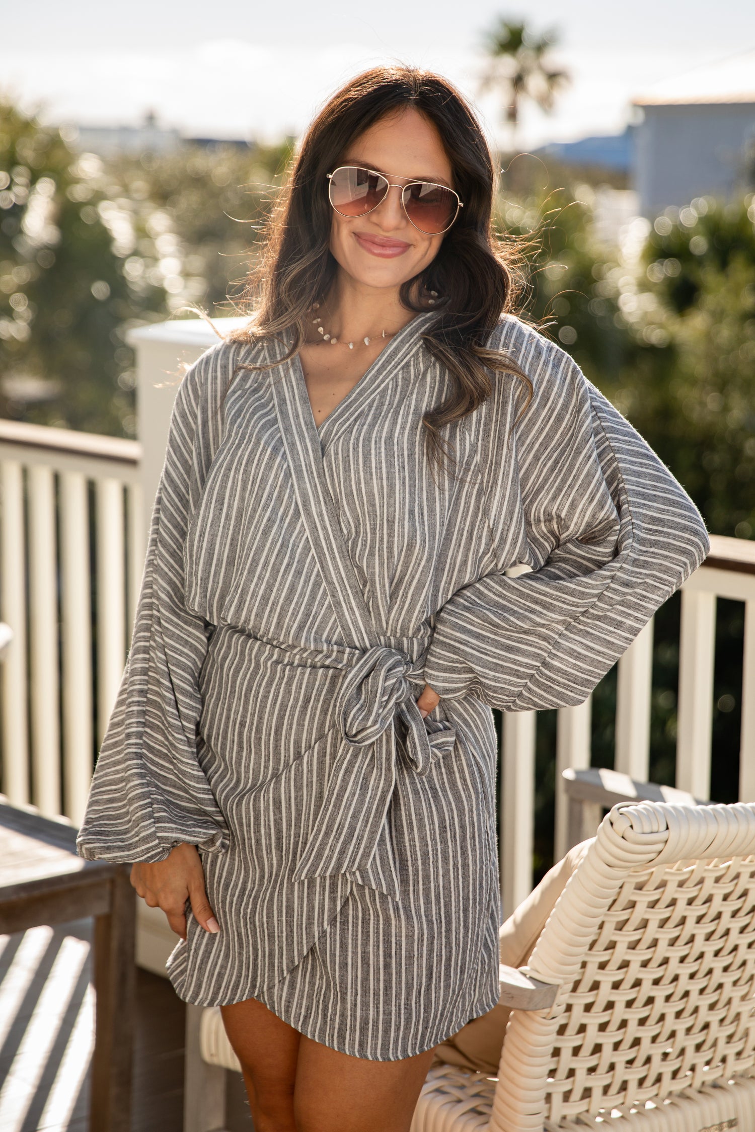 Woman wearing a striped robe on a balcony with greenery in the background