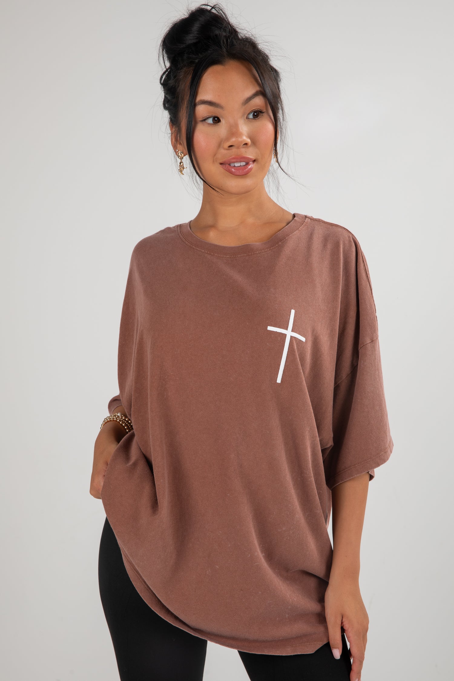 Woman wearing a brown oversized shirt with a white &