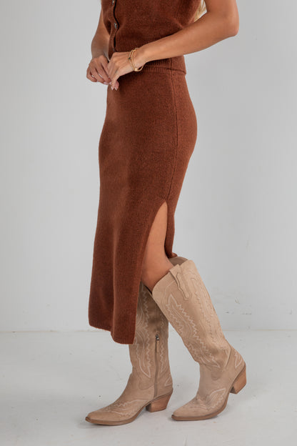 Person wearing a brown suede skirt and beige boots on a plain background