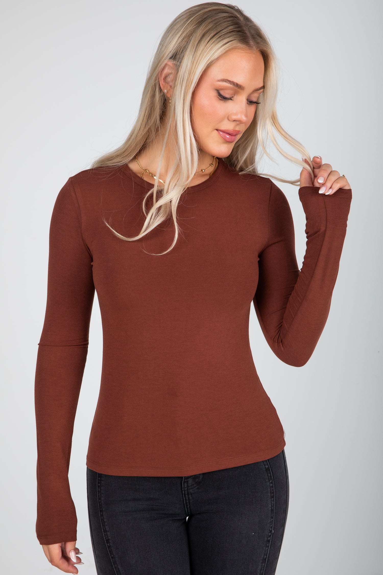 Woman wearing a brown long-sleeve top against a white background