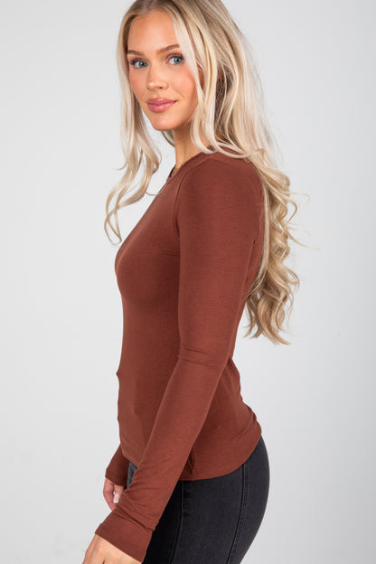 Woman wearing a brown long-sleeve top against a white background