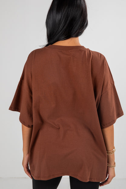 Brown oversized t-shirt worn by a person on a white background