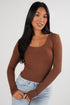 Woman wearing a brown long-sleeve top and light blue jeans on a white background