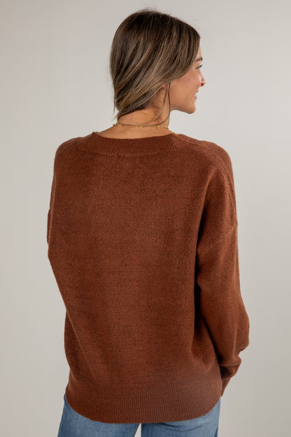 Woman wearing a brown sweater against a plain background