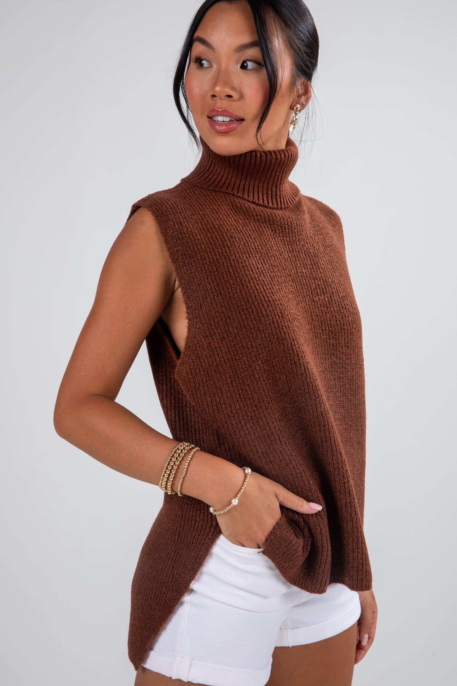 Woman wearing a brown sleeveless knit top with a plain background