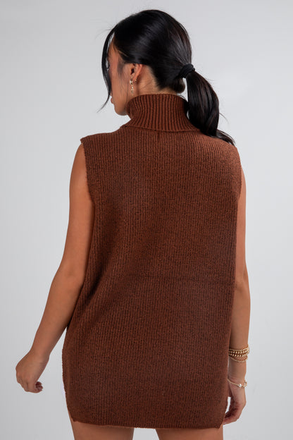 Woman wearing a brown knitted sleeveless dress against a white background