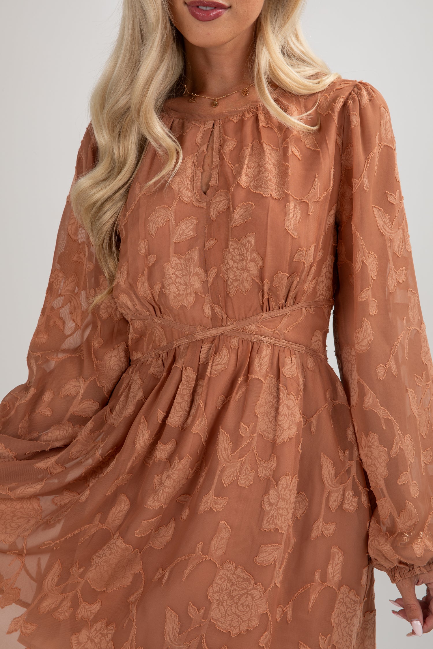 Woman wearing a brown floral dress against a plain background