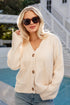 Woman wearing a cream cardigan and sunglasses outdoors by a pool