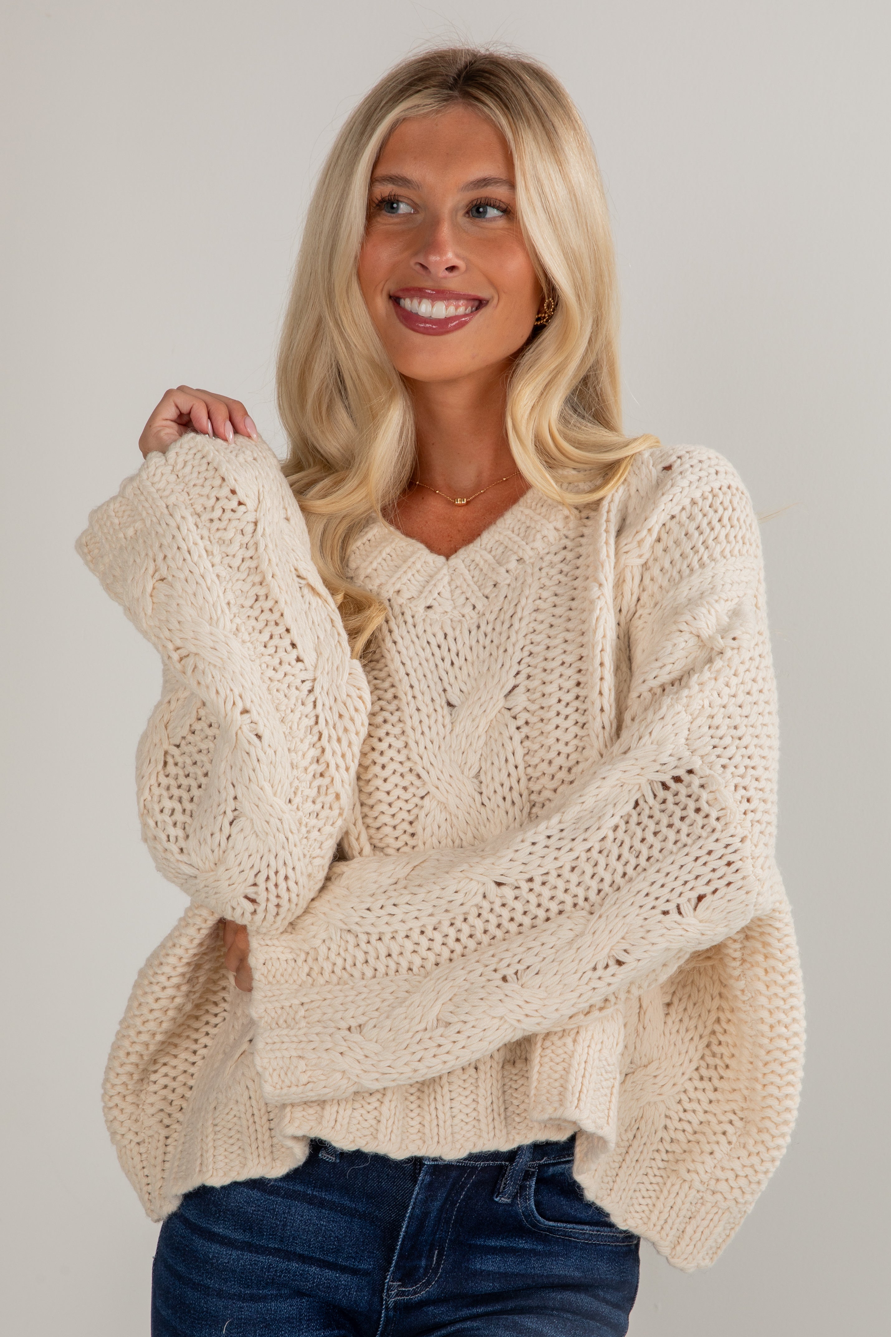 Woman wearing a beige knitted sweater against a plain background