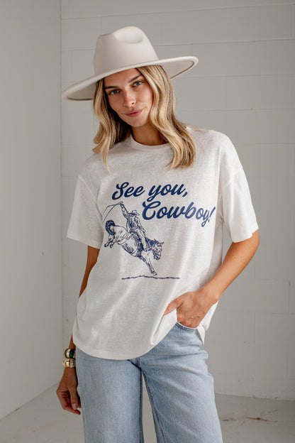 A woman wearing a white graphic t-shirt with a blue &