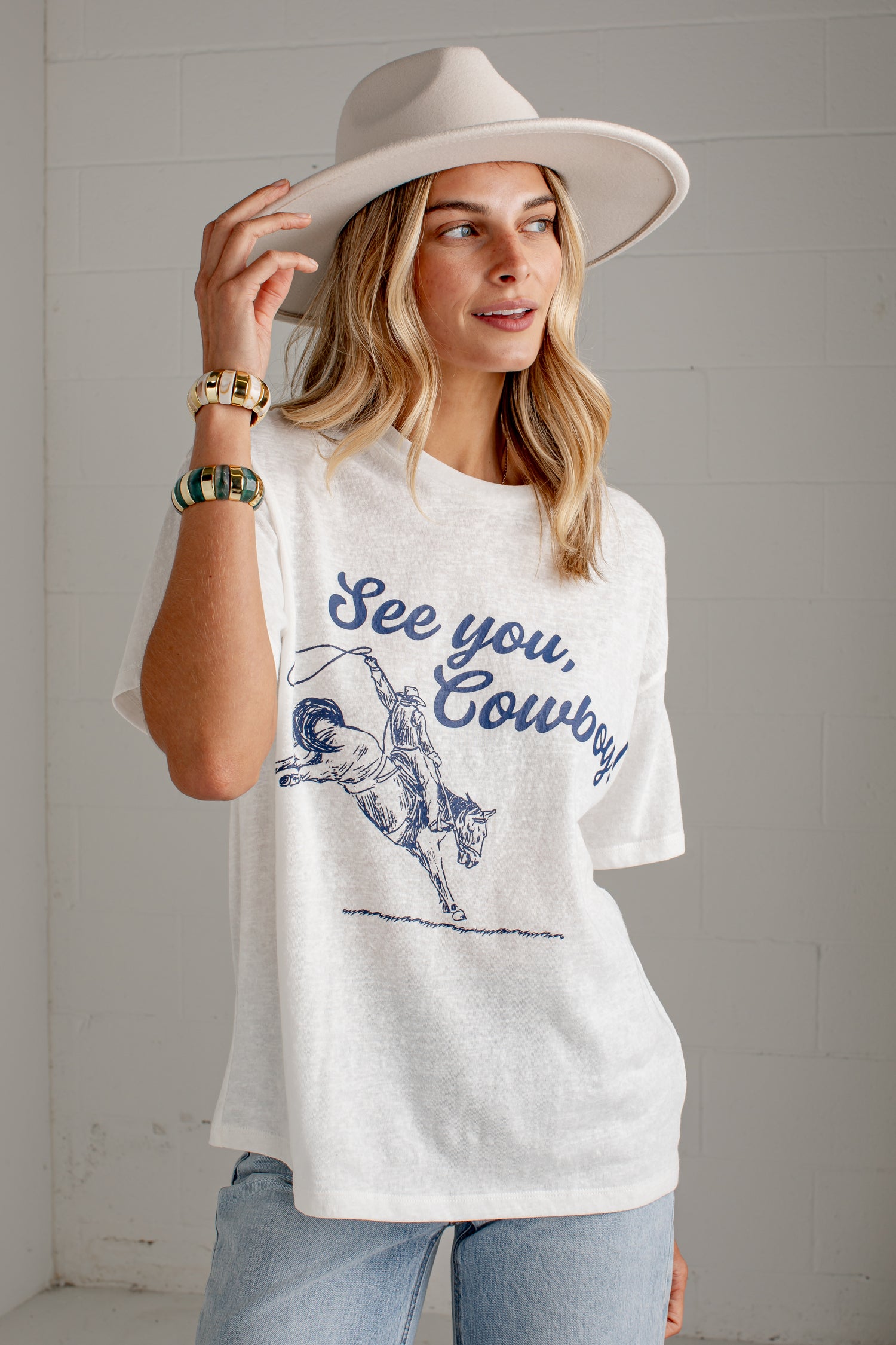 A woman wearing a white graphic t-shirt with a blue &