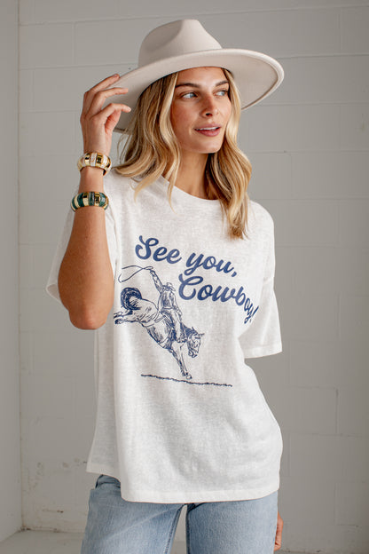 A woman wearing a white graphic t-shirt with a blue &