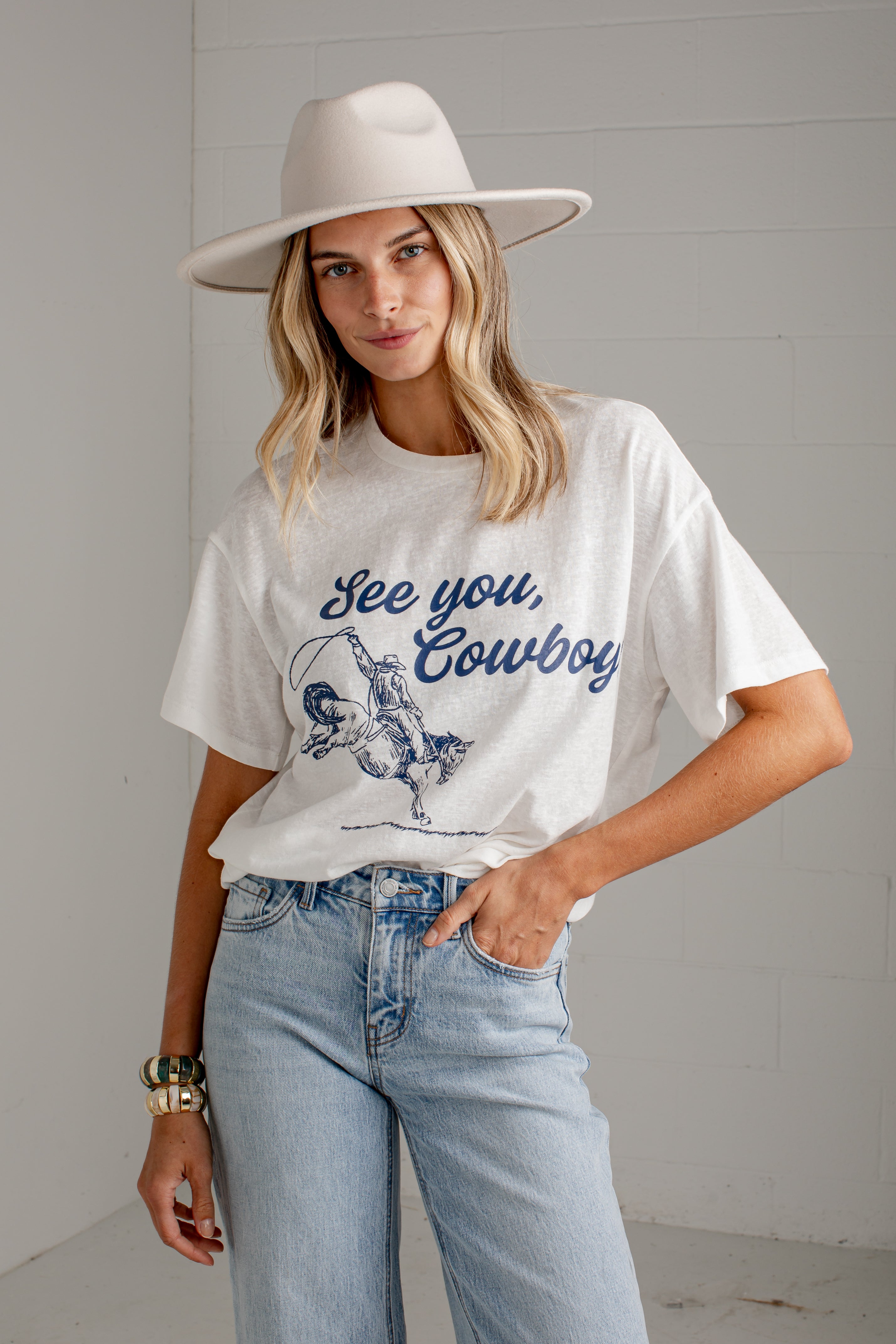 A woman wearing a white graphic t-shirt with a blue &