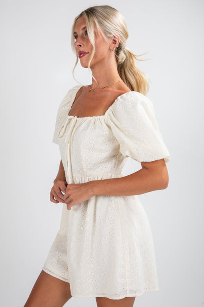 Woman wearing a white dress with puff sleeves against a plain background