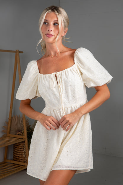 Woman wearing a white dress with puff sleeves in a minimal indoor setting