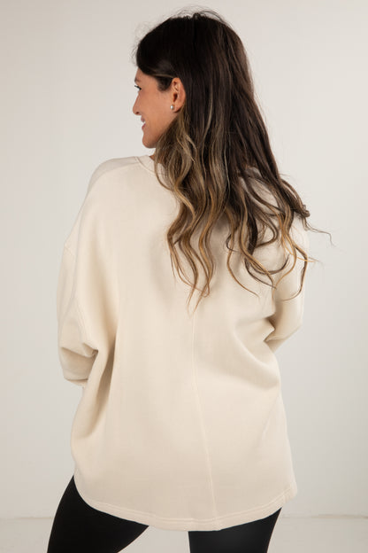 Woman wearing a beige sweater with a plain white background