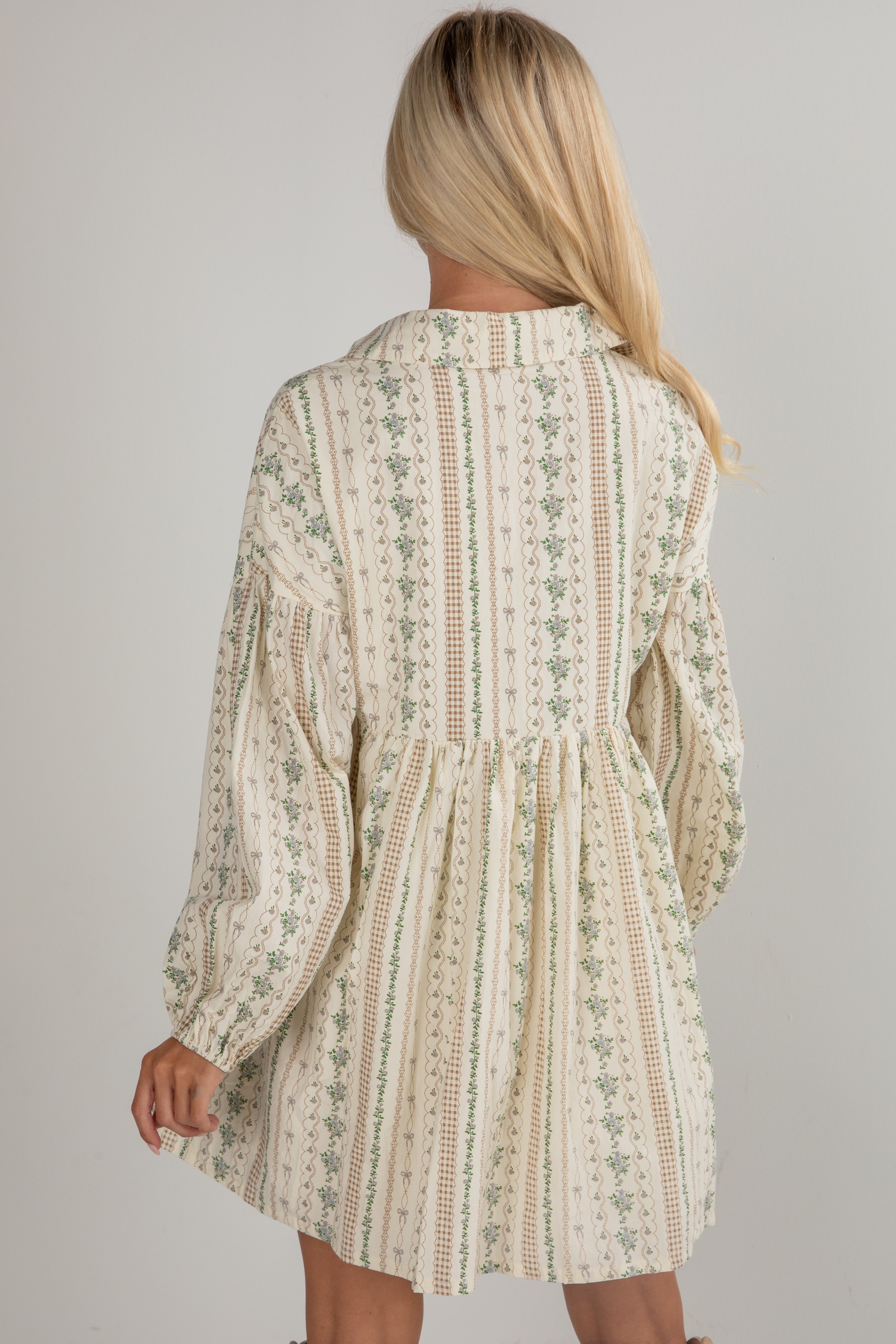 Woman wearing a patterned dress with long sleeves on a plain background